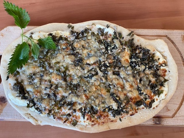 Wildkräuterflammkuchen auf einem Holzbrett